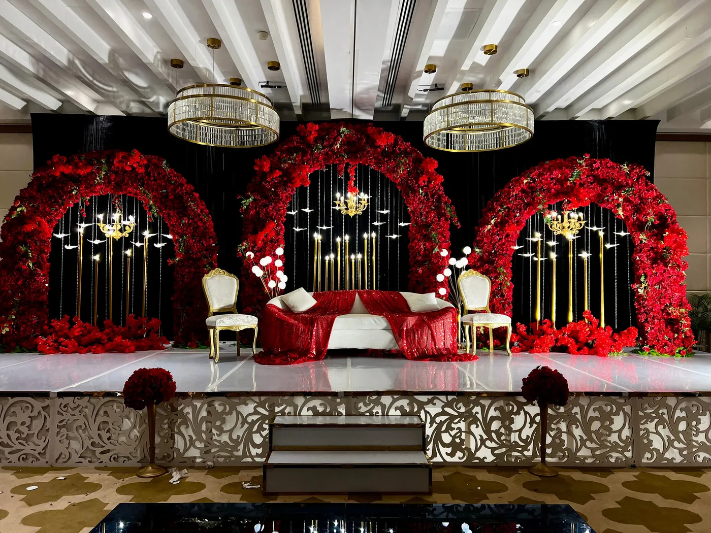 Red rose arches and chandeliers on a wedding stage